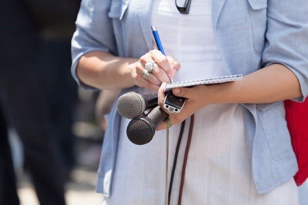A Press Reporter Holding Microphones For Press Meet.