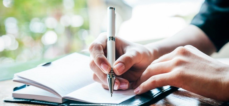 A Journalist Writing His Own Journal In A Notebook.